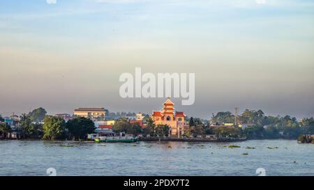 Eine Kirche im östlichen Stil und andere Gebäude am Ufer des Mekong bei Long Xuyen im Mekong Delta in Vietnam. Stockfoto