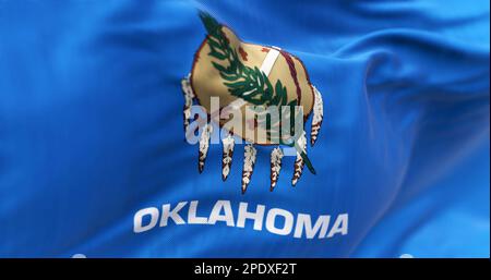 Detail der Oklahoma Staatsflagge, die winkt. Blaues Feld mit Büffelhautschild, Olivenzweig und Friedenspfeife. Geriffelter Stoff. Strukturierter Hintergrund. Stockfoto