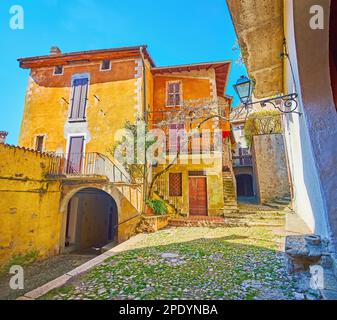 Die winzige alte Piazza Paolo Pagani mit kleinen historischen Häusern, Bogenpässen und Gassen, die in verschiedene Richtungen führen, Castello, Valsolda, Italien Stockfoto