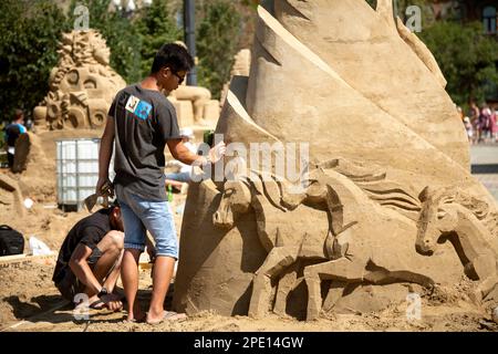 Khabarowsk, Russland - 30. August 2014: Sandskulpturenfestival - zwei junge Künstler, die an einer Pferdefigur arbeiten. Kunstwettbewerb am Strand im Freien Stockfoto