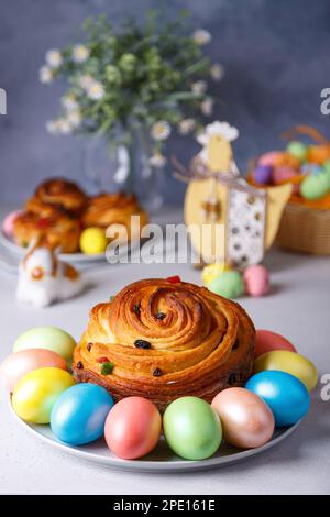 Craffin (Cruffin) mit Rosinen und kandierten Früchten. Traditionelles Osterbrot Kulich und bemalte Eier auf grauem Hintergrund. Osterferien. Nahaufnahme. Stockfoto
