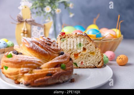 Craffin (Cruffin) mit Rosinen und kandierten Früchten. Traditionelles Osterbrot Kulich und bemalte Eier auf grauem Hintergrund. Osterferien. Nahaufnahme. Stockfoto