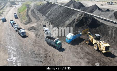 Radlader, der Kohle auf Lkw lädt und auf einer riesigen Bergbaustelle arbeitet. Stockfoto