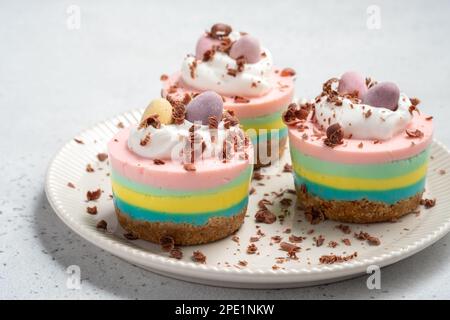 Ostern-Mini-Käsekuchen mit Zuckereiern und Schlagsahne. Stockfoto