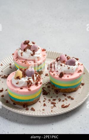 Ostern-Mini-Käsekuchen mit Zuckereiern und Schlagsahne. Stockfoto