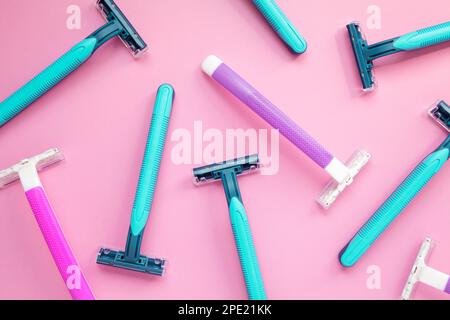 Viele Einweg-Rasierer in lila und blau auf einem rosa Hintergrund. Bunte Frauen und Männer Hygiene-Zubehör flach legen Stockfoto