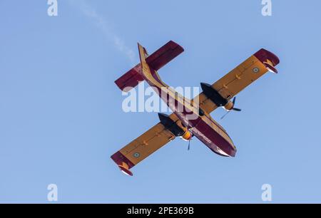 Canadair Feuerwehrflugzeug, Scooper fliegt auf blauem Himmel Hintergrund, unter Sicht. Gelbrote Farbe Wasserflugzeug Flug für Rettung und Transport. Stockfoto