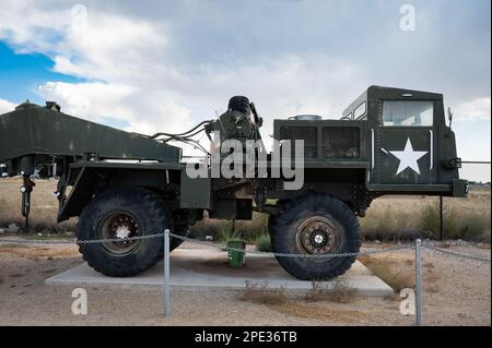 Ein olivgrüner Militärwagen steht auf einer Betonplattform in einem hellblauen Himmel Stockfoto