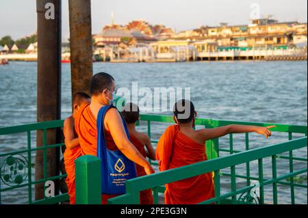 Januar 3 2023 - Bangkok Thailand - buddhistischer Mönch, traditionell in Orange gekleidet, der mit seinem Handy am Flussufer in Bangk Fotos von jungen Mönchen macht Stockfoto