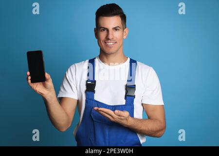 Techniker mit modernem Smartphone auf blauem Hintergrund Stockfoto