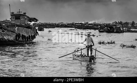 Eine Frau steht da, um ihren Nudelstand zu einer Gemeinde zu rudern, die auf Booten auf dem Mekong Fluss, nahe Long Xuyen im Mekong Delta, Vietnam, lebt. Stockfoto