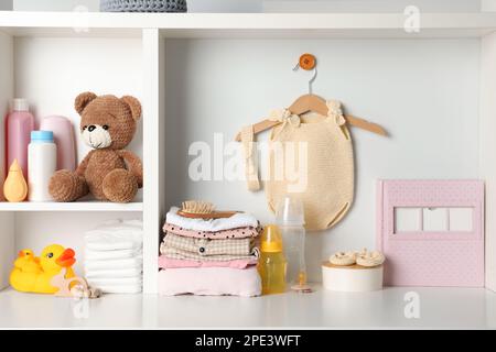 Babykleidung, Spielzeug und Accessoires auf weißem Gestell Stockfoto