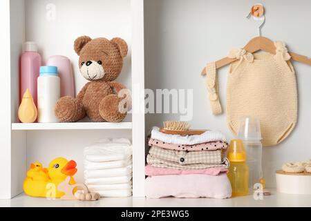 Babykleidung, Spielzeug und Accessoires auf weißem Gestell Stockfoto