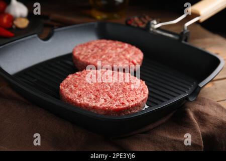 Rohe Hamburger-Pasteten mit Öl auf der Grillpfanne, Nahaufnahme Stockfoto
