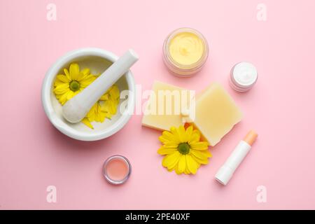 Flache Laienzusammensetzung mit Bienenwachs und kosmetischen Mitteln auf pinkfarbenem Hintergrund Stockfoto