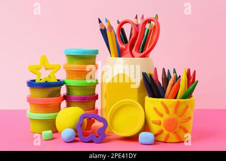 Set aus hellem Teig mit Werkzeugen und Bleistiften auf farbigem Hintergrund Stockfoto