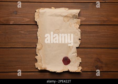 Blatt altes Pergamentpapier mit Wachsstempel auf Holztisch, Draufsicht. Raum für Design Stockfoto