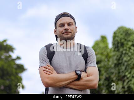 Porträt eines jungen Reisenden mit Rucksack, der in die Kamera schaut. Stockfoto