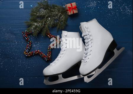 Ein Paar Schlittschuhe mit weihnachtlicher Einrichtung auf blauem Holzhintergrund, flach liegend Stockfoto
