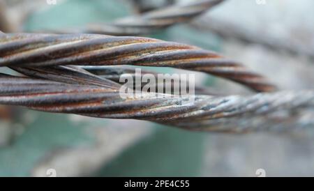 Nahaufnahme von mehreren verdrehten Metallsträngen vor grünem, verschwommenem Hintergrund Stockfoto