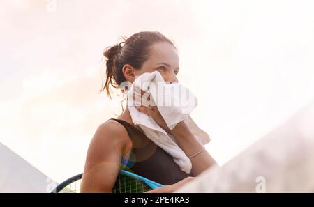 Sportlerin, die sich nach dem Tennisspiel mit einem Handtuch das Gesicht abwischt. Stockfoto