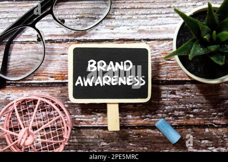 Technologiekonzept. Draufsicht Schwarze Sprechblase schriftliche MARKENBEKANNTHEIT mit Lupe isoliert auf gelbem Hintergrund. Stockfoto