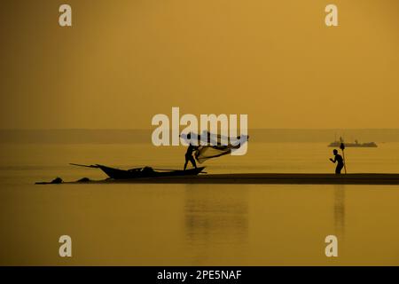 „Fisherman's Night Fishing Moment“-Silhouette. Er fing abends mit seinem Netz Fische im Fluss Padma, einem der berühmten Flüsse von Bangladesch Stockfoto