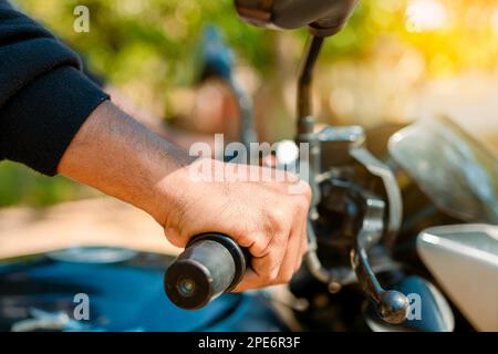 Hände eines Mannes am Lenker des Motorrads. Motorrad-Geschwindigkeitskonzept, Hände eines Motorradfahrers am Lenker. Nahaufnahme der Hände am Stockfoto