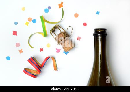 Champagnerflasche, Champagnerkorken, Luftschlangen und Konfetti vor weißem Hintergrund Stockfoto