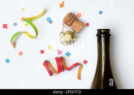 Champagnerflasche, Champagnerkorken, Luftschlangen und Konfetti vor weißem Hintergrund Stockfoto