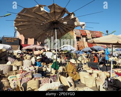 Marrakesch, Marokko - 31. Dezember 2019: Unbekannter einheimischer Mann, der Strohkörbe und Taschen im Souk verkauft - typischer marokkanischer Straßenmarkt, weitere Geschäfte im Hintergrund Stockfoto