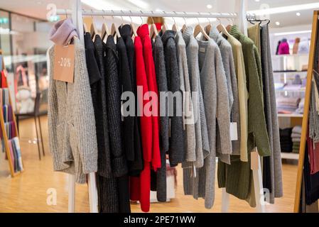 Stilvolle Kleidung hängt an Kleiderbügeln in einem Geschäft in einem Einkaufszentrum Stockfoto