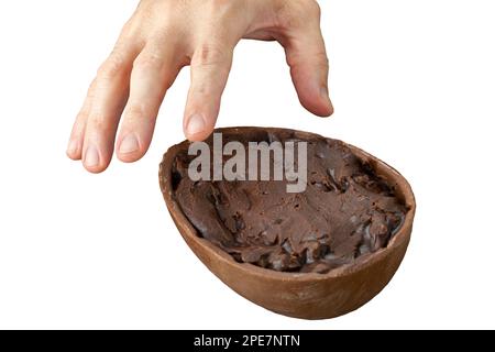 Männerhand, die Schokolade aufnimmt osterei gefüllt mit Nüssen und dunkler Schokolade. Stockfoto