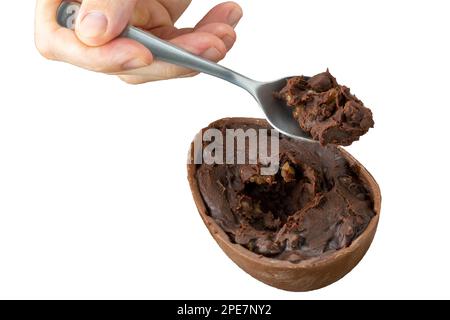 Erwachsene Hand, die mit einem Löffel Schokoladen-ostereier-Füllung aufsaugt. Stockfoto