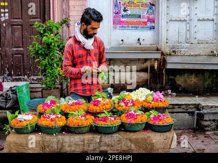 Ein Mann, der farbenfrohe Blumengirlanden vor einem Chandni Chowk Tempel in Old Delhi verkauft Stockfoto