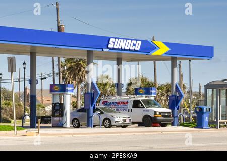 Galveston, Texas, USA - Februar 2023: Auto und Lieferwagen werden an einer Tankstelle am Meer betankt. Die Tankstelle wird von Sunoco betrieben. Stockfoto