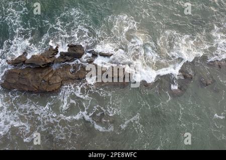 Meereswellen bedecken Steinfelsen aus der Vogelperspektive Stockfoto