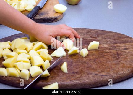 Schneiden Sie die Kartoffeln in Stücke Stockfoto