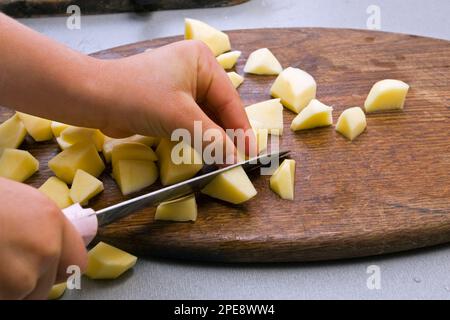 Schneiden Sie die Kartoffeln in Stücke Stockfoto