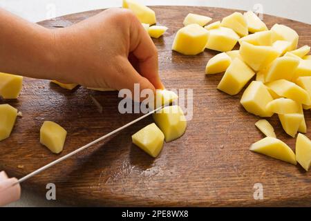 Schneiden Sie die Kartoffeln in Stücke Stockfoto