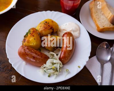 Gegrillte Fleischwürste serviert mit Kartoffeln, gebraten mit Zwiebeln Stockfoto