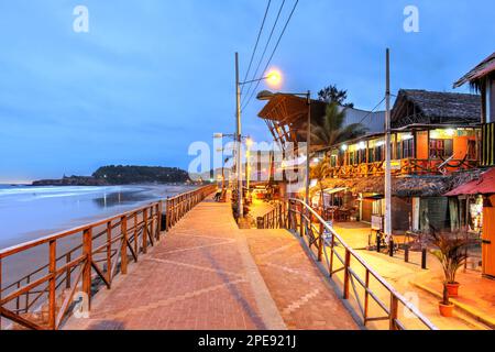 Abendszene entlang der Uferpromenade des Surfdorfes Montanita in Ecuador mit breiten weißen Stränden. Stockfoto