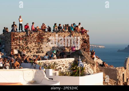 Touristen beobachten den Sonnenuntergang über dem Meer auf dem Dach von Häusern im Dorf Oia Greek Island Stockfoto