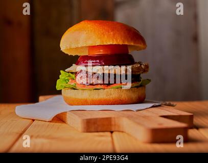 Saftiger Käseburger auf einer Holzfläche mit Holzhintergrund Stockfoto