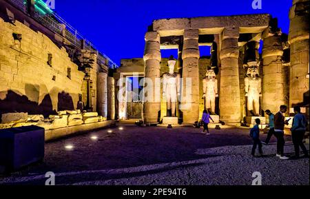 Mit Flutlicht beleuchtete Statuen von König Ramesses II. Im ersten Hof des Tempels Luxor. Stockfoto