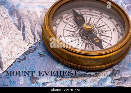 Selektiver Fokus Nahaufnahme eines klassischen Messingkompasses auf Kartendetails von Mt. Topografische Karte des Everest mit Konturlinien, Höhe Stockfoto