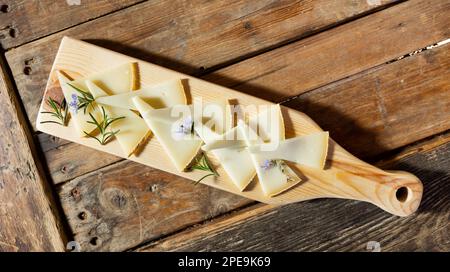 Scheiben von handwerklich hergestelltem Ziegenkäse mit blühendem Rosmarin zur Verkostung Stockfoto