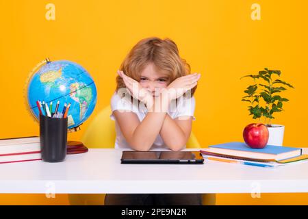 Hör auf, mich zu schikanieren Traurige und wütende Schülerin. Schulkind, das in der Grundschule im Klassenzimmer studiert. Ein Kind, das im Unterricht auf gelbem isoliertem Hintergrund lernt Stockfoto