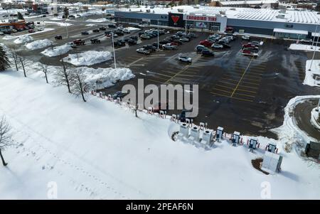 Ein Hochwinkel-Luftbild mit Blick auf eine große Tesla Supercharger-Station auf einem Parkplatz in Kanada in der Wintersaison mit Schnee auf dem Boden. Stockfoto