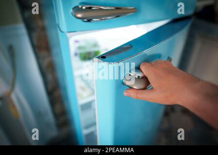 Mann öffnet die Tür des Retro-Kühlschranks. Stockfoto